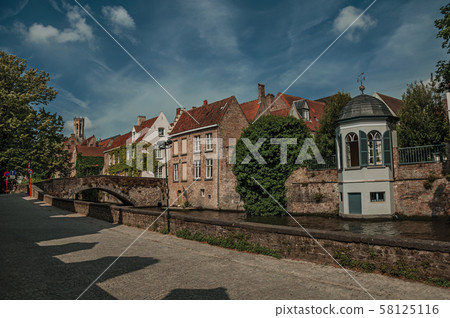 Bridge and brick buildings with creeper on canal of Bruges 58125116