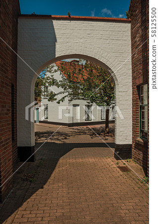 Portal to enter a square with old brick house in Bruges Portal to enter a square with old brick house in Bruges 58125500