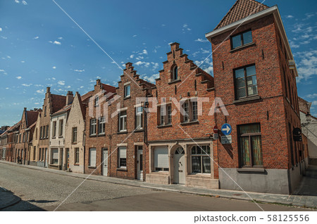 Brick facade of old houses in a street of Bruges 58125556