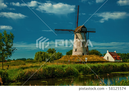Old windmill next to canal with bushes and grove near Damme 58125574