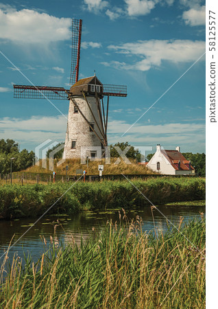 Old windmill next to canal with bushes and grove near Damme Old windmill next to canal with bushes and grove near Damme 58125577