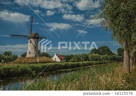 Old windmill next to canal with bushes and grove near Damme Old windmill next to canal with bushes and grove near Damme 58125578