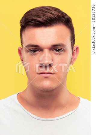 Caucasian young man's close up portrait on yellow background 58125736