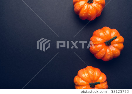 Dark background with three pumpkins. 58125753