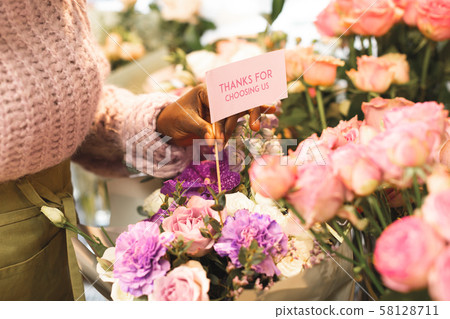Close up of female hand that putting card into bouquet Close up of female hand that putting card into bouquet 58128711