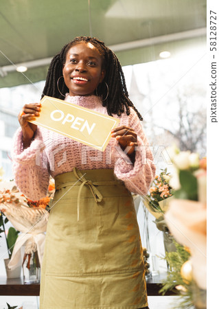 Happy international florist welcoming guests in her shop 58128727