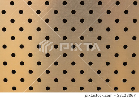Close-up of metal surface of golden color of smooth wall with round openings Close-up of metal surface of golden color of smooth wall with round openings 58128867