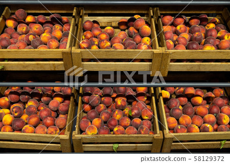 Wooden lug boxes with soft and mellow peaches on counter in supermarket 58129372