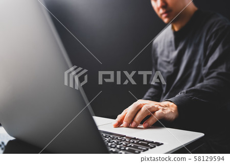 attractive asian man in black using laptop computer in modern home office attractive asian man in black using laptop computer in modern home office 58129594