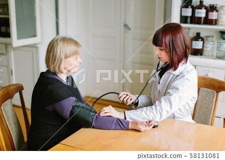 Woman pharmacist checking woman patient arterial blood pressure. Health care. Woman pharmacist checking woman patient arterial blood pressure. Health care. 58131081