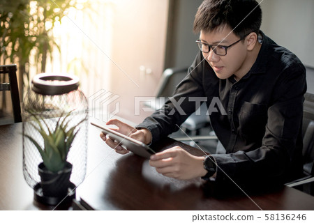 Asian businessman using digital tablet in office Asian businessman using digital tablet in office 58136246