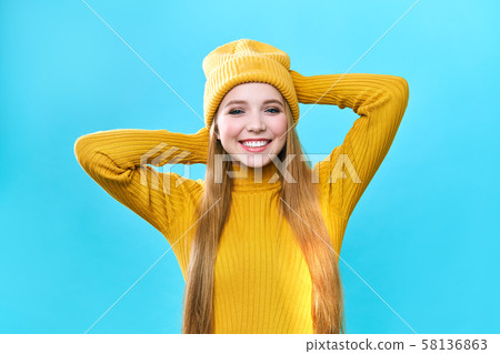 Portrait of a beautiful girl, in a yellow hat and sweater, looking at the camera and smiling cute. Portrait of a beautiful girl, in a yellow hat and sweater, looking at the camera and smiling cute. 58136863