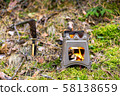 Burning foldable wood stove designed for cooking outdoors using twigs as fuel on nature background 58138659