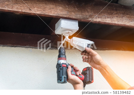 Technician installing IP wireless CCTV camera by screwed for home security system and installed white plastic boxes for safe from water and rain 58139482