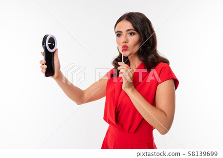 secretary on the background of a white wall corrects makeup, a girl looks in a smartphone and paints 58139699