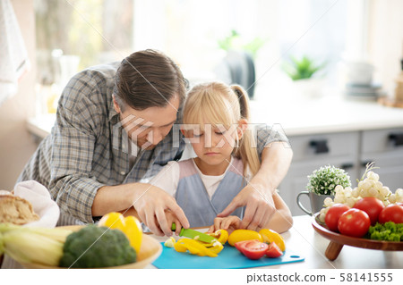 Handsome daughter assisting daughter while cutting vegetables Handsome daughter assisting daughter while cutting vegetables 58141555