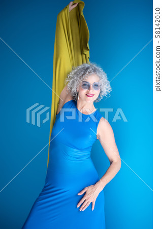 Good-looking mature lady wearing long blue dress posing Good-looking mature lady wearing long blue dress posing 58142010