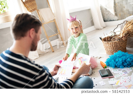 Little schoolgirl showing her paintings to father after school 58142553