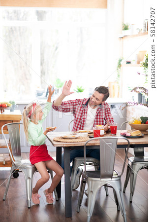 Daughter giving high five to father while having yummy breakfast Daughter giving high five to father while having yummy breakfast 58142707