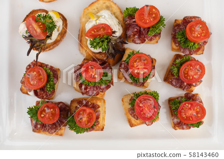 Delicious canape with sausage and tomato.Canapes 58143460