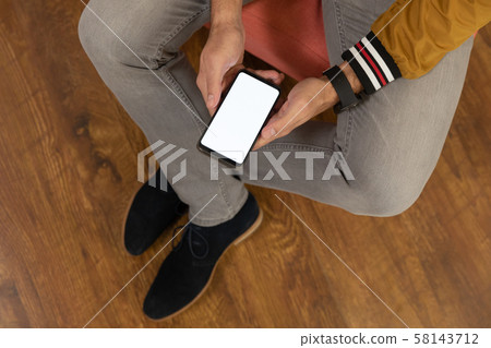 Young man at home using a smartphone Young man at home using a smartphone 58143712