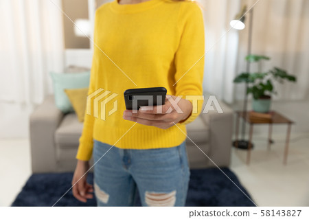 Young woman at home using a smartphone Young woman at home using a smartphone 58143827