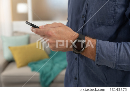 Young man at home using a smartphone Young man at home using a smartphone 58143873