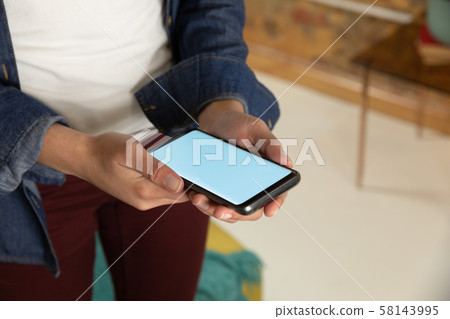 Young woman at home using a smartphone Young woman at home using a smartphone 58143995