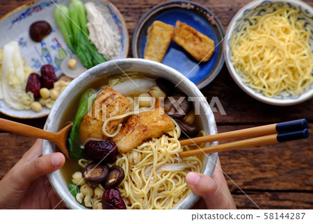 woman hand hold Vietnamese vegan noodles soup on ingredients food background 58144287