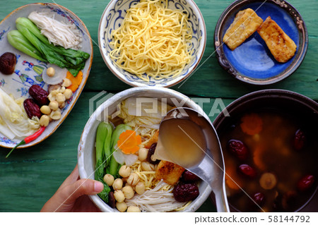 People prepare vegetarian homemade noodle soup bowl from vegan ingredient People prepare vegetarian homemade noodle soup bowl from vegan ingredient 58144792