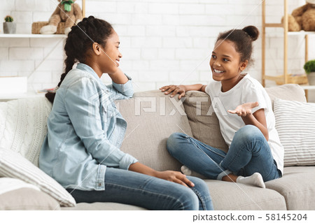 Two lovely black sisters having conversation at home 58145204