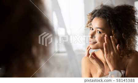 Positive Afro Girl Applying Eye Cream Preventing Wrinkles In Bathroom Positive Afro Girl Applying Eye Cream Preventing Wrinkles In Bathroom 58145388