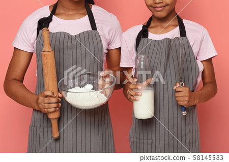 Cropped image of black sisters holding kitchen tools 58145583