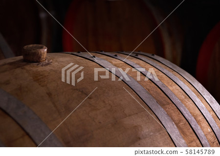 wooden barrel on a dark background, in a workshop wooden barrel on a dark background, in a workshop 58145789