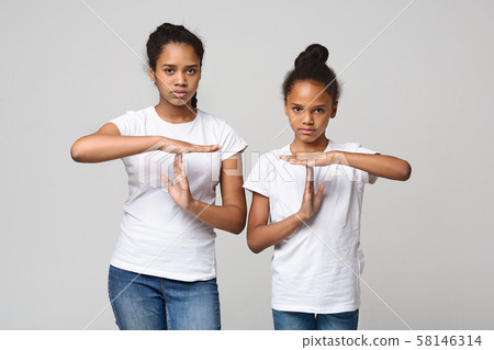 Two beautiful girls showing time out sign over grey background 58146314