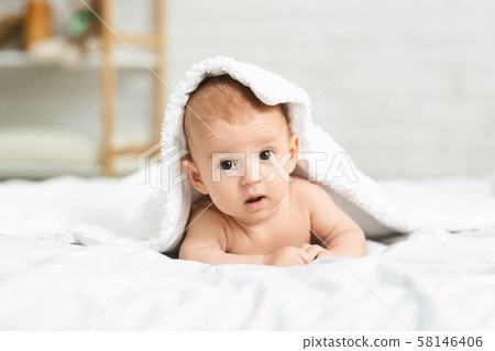 Portrait of cute newborn boy peeking out from under blanket Portrait of cute newborn boy peeking out from under blanket 58146406