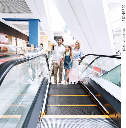 Parents And Daughter Going Up On Escalator In Shopping Center Parents And Daughter Going Up On Escalator In Shopping Center 58146801