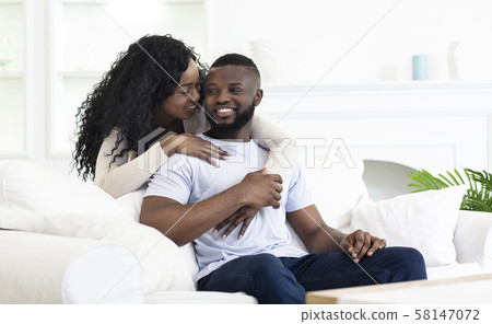 Playful african american woman whispering something to her boyfriend's ear 58147072