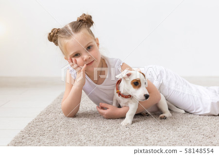 people, children and pets concept - little child girl lying on the floor with cute puppy Jack people, children and pets concept - little child girl lying on the floor with cute puppy Jack 58148554