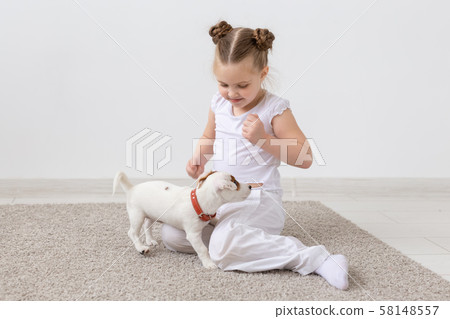 Animals, children and pets concept - little child girl sitting on the floor with cute puppy and Animals, children and pets concept - little child girl sitting on the floor with cute puppy and 58148557
