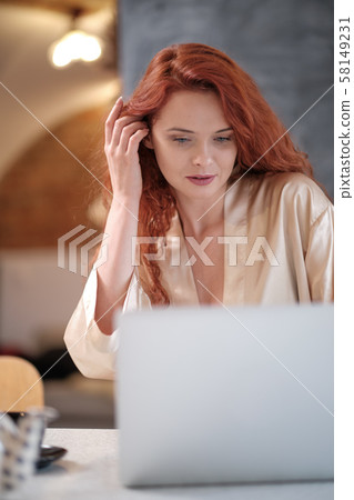 Woman in a bathrobe works on a laptop at home Woman in a bathrobe works on a laptop at home 58149231