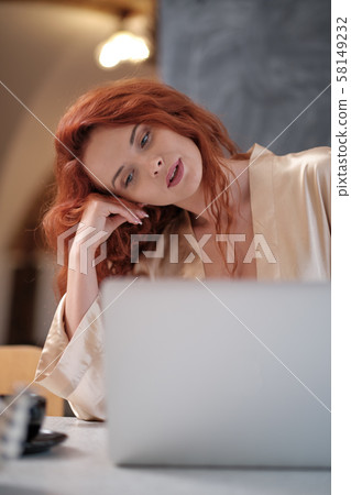 Woman in a bathrobe works on a laptop at home 58149232