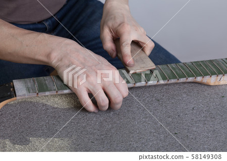 the master polishes the frets on the fretboard of the guitar. The fingerboard is protected by molar the master polishes the frets on the fretboard of the guitar. The fingerboard is protected by molar 58149308