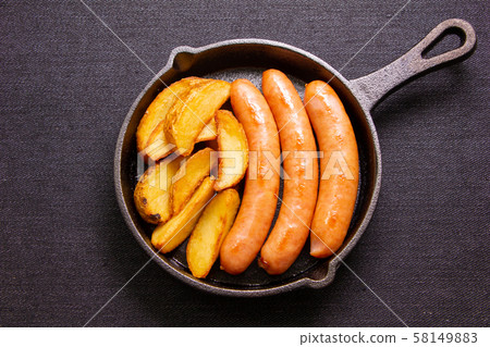 煎鍋中分類的維也納香腸和炸薯條（帶皮）。 58149883