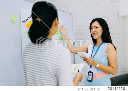 Positive Asian businesswoman doing presentation for colleague 58150658