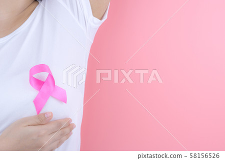 Healthcare, medicine and breast cancer awareness concept. Closeup woman hands holding pink breast cancer awareness ribbon. 58156526