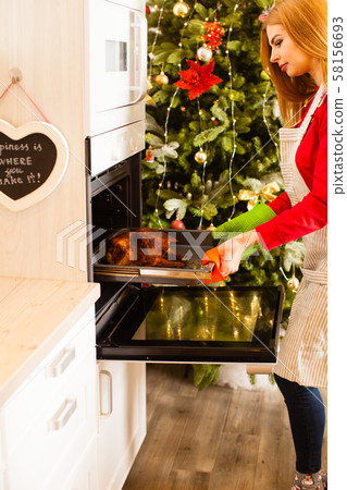Housewife prepares roast chicken in the oven 58156693