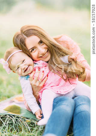 Happy cheerful family. Mother and baby kissing, laughing and hugging in nature outdoors Happy cheerful family. Mother and baby kissing, laughing and hugging in nature outdoors 58157028