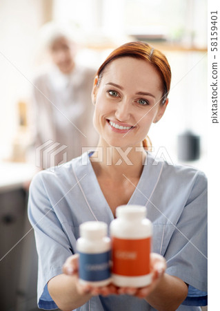 Caregiver holding vitamins and supplements for patient 58159401