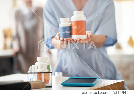 Close up of medical attendant holding packs of vitamins 58159403